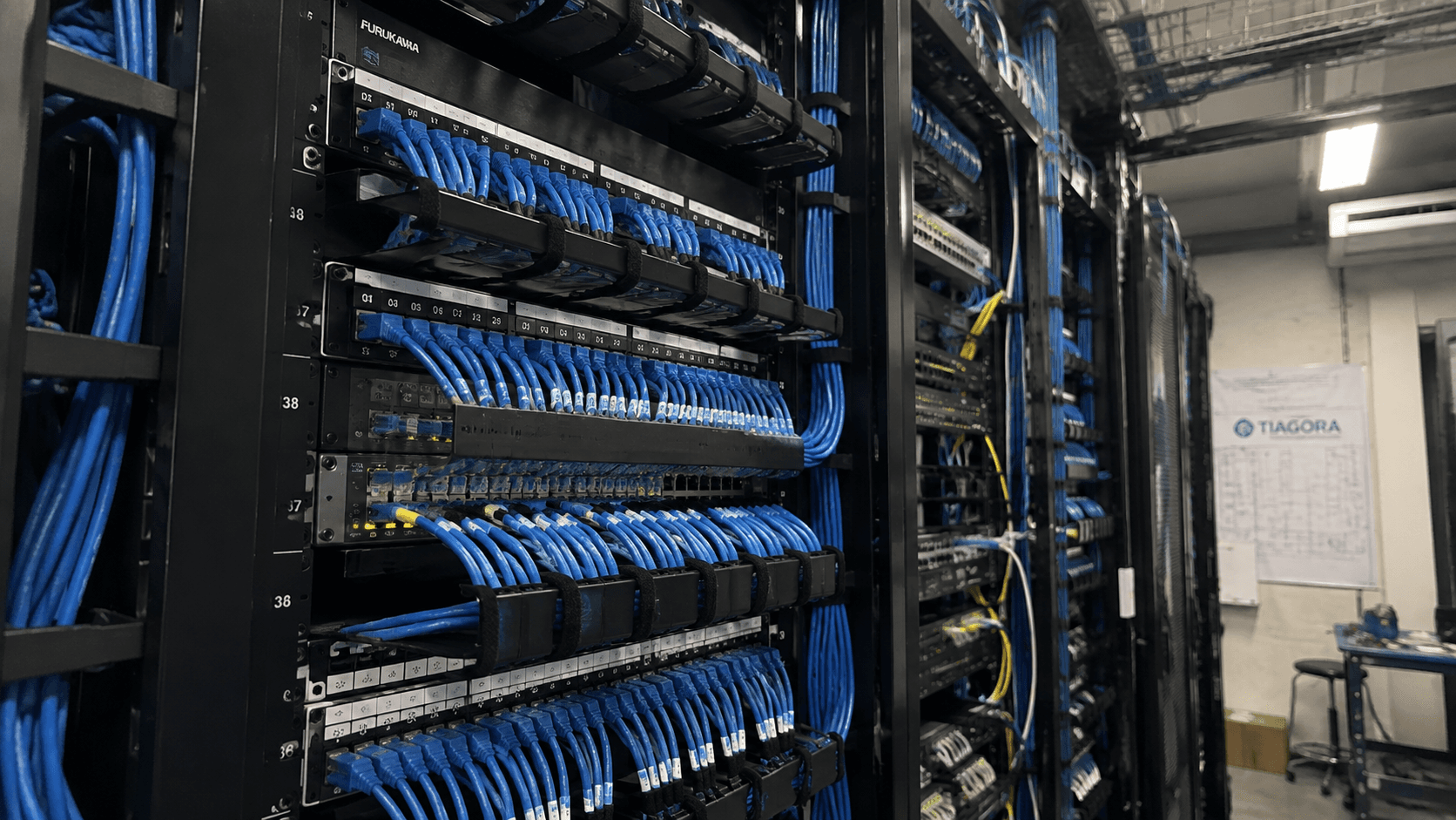 Rack de telecomunicações com cabeamento estruturado azul organizado, instalado pela Tiagora